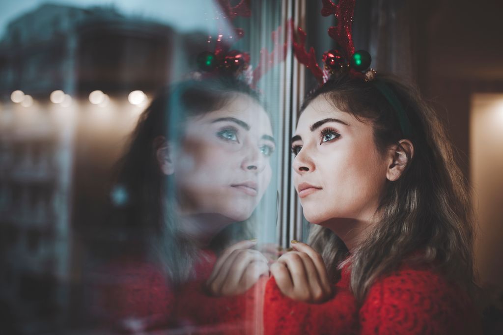 Woman wearing sparkly antlers looking out a window