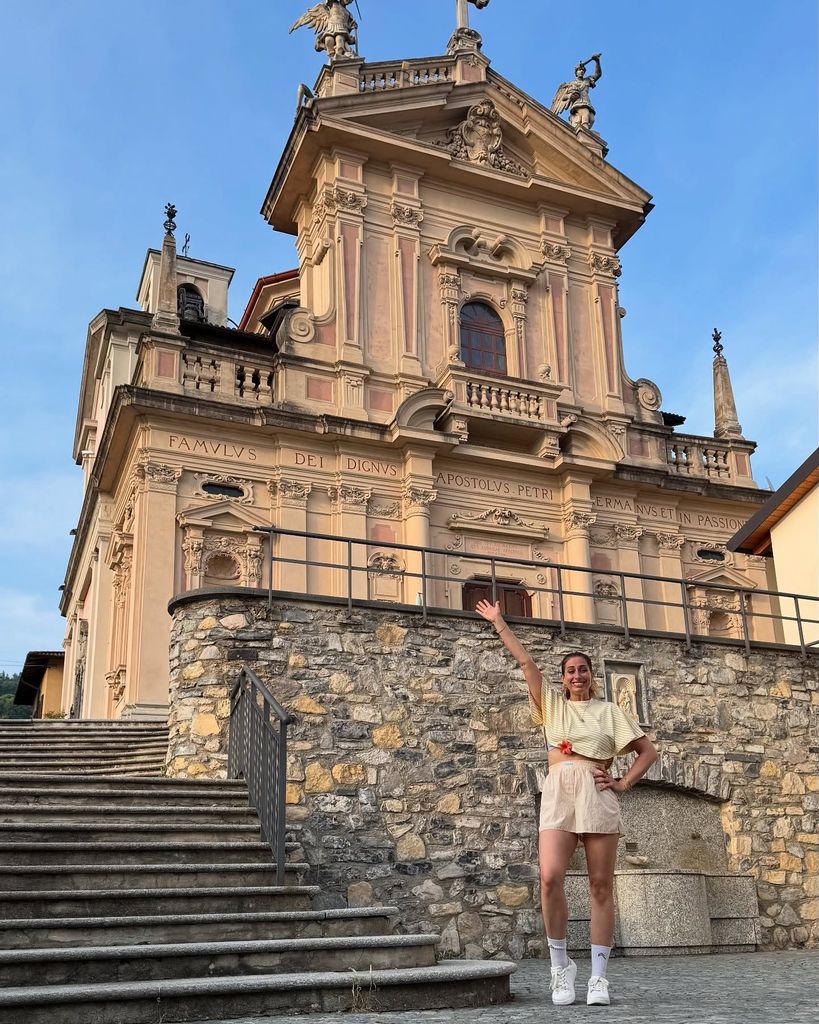 stacey solomon posing with one arm in the air in front of striking building