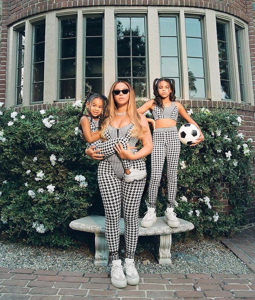 Beyonce stood in a garden with Rumi in her arms and Blue Ivy stood with a soccer ball behind her