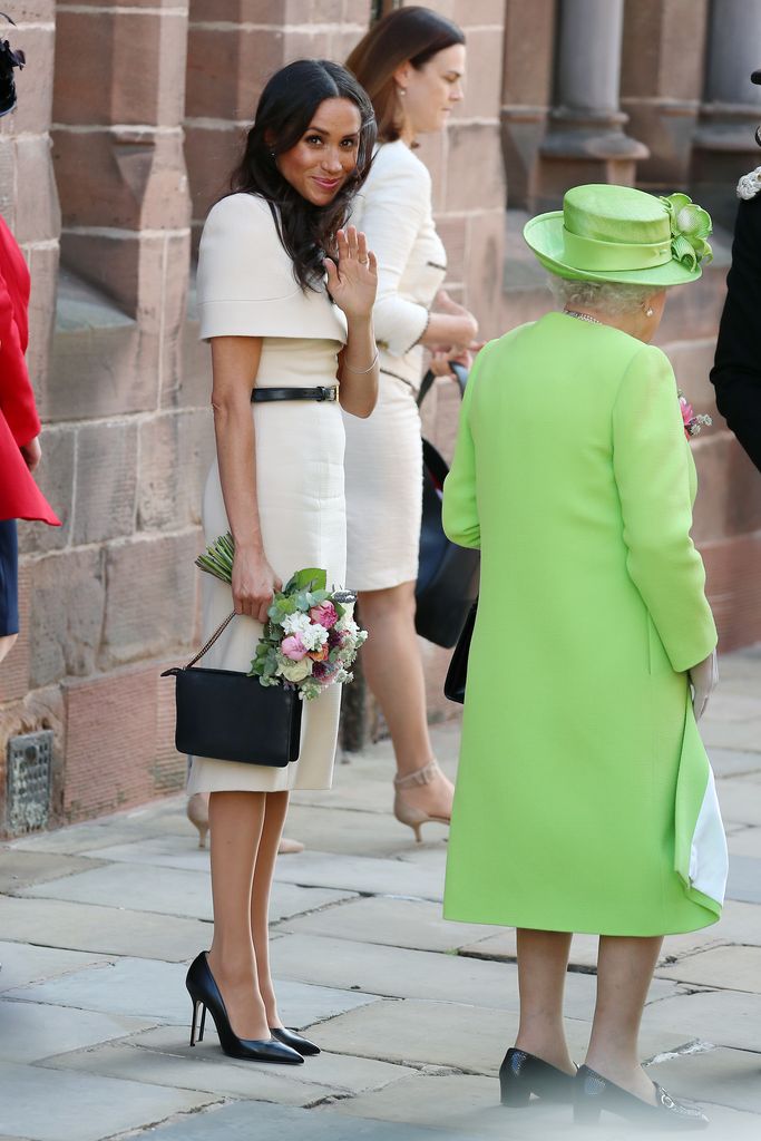 Queen Elizabeth II in green and Meghan in white waving to crowds