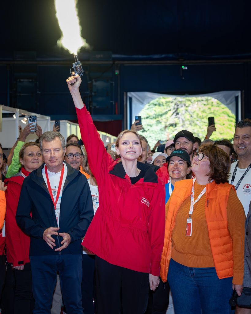 Princess Charlene firing gun in red coat