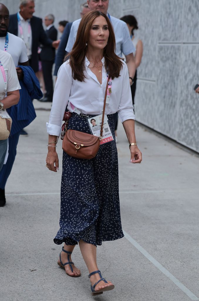 Queen Mary walking in navy skirt and white shirt