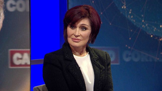Sharon Osbourne during an interview wearing a black suit and white top