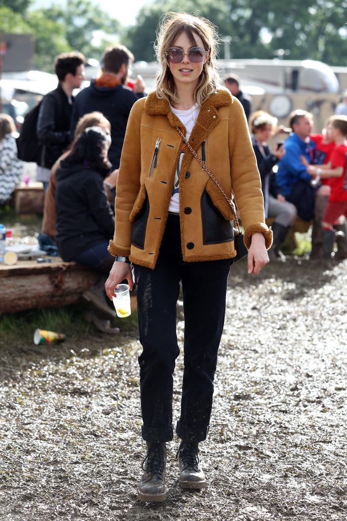  Edie Campbell attends the Glastonbury Festival in 2016 wearing black jeans, a brown coat and pair of sunglasses