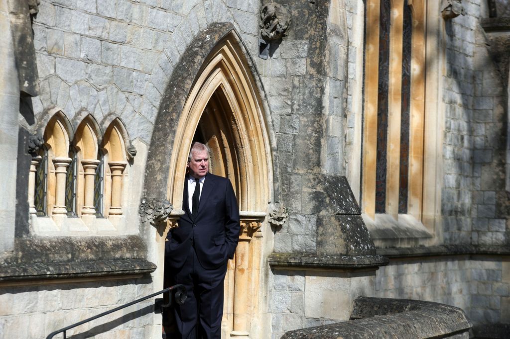 man in black suit looking out of church door 