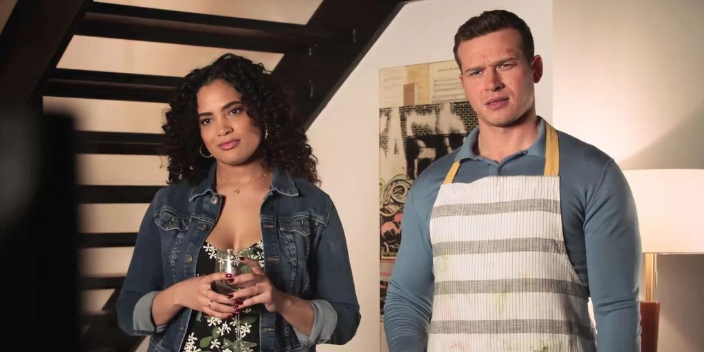 Natalia and Buck in 911 stand in his loft, she holds a glass of wine and he is wearing apron
