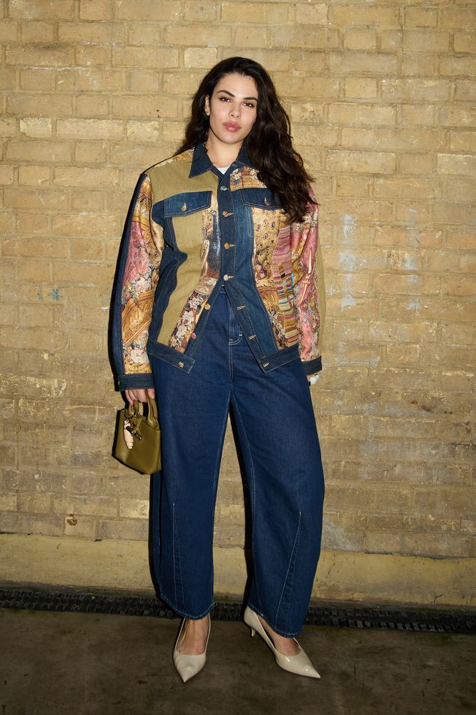 Shay Zanco assiste au défilé Kseniaschnaider portant une chemise en jean à motifs patchwork et un jean en denim bleu avec des talons et un mini sac olive lors de la Fashion week de Londres en février 2026 