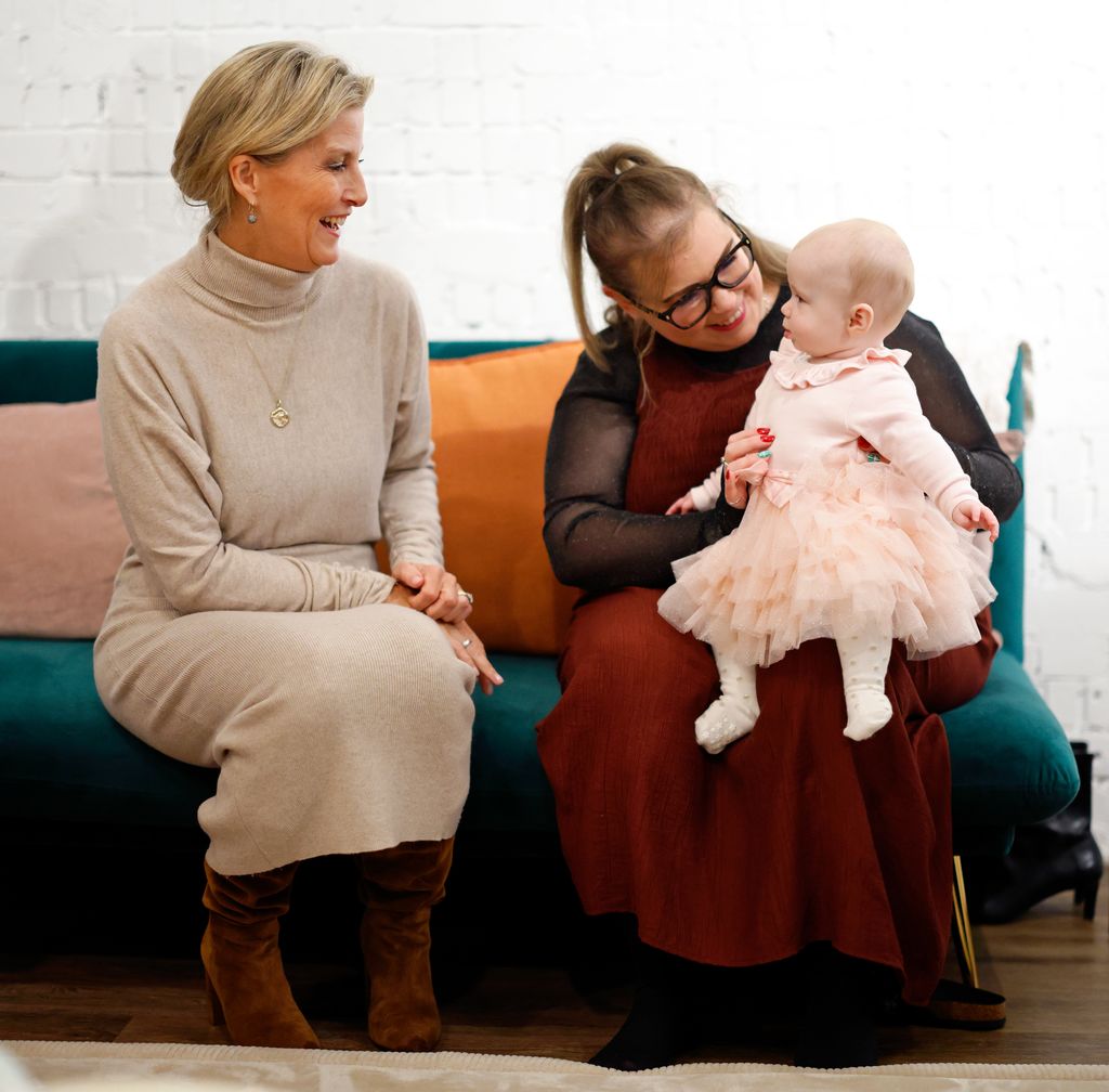 Sophie talking to mother holding baby sat down