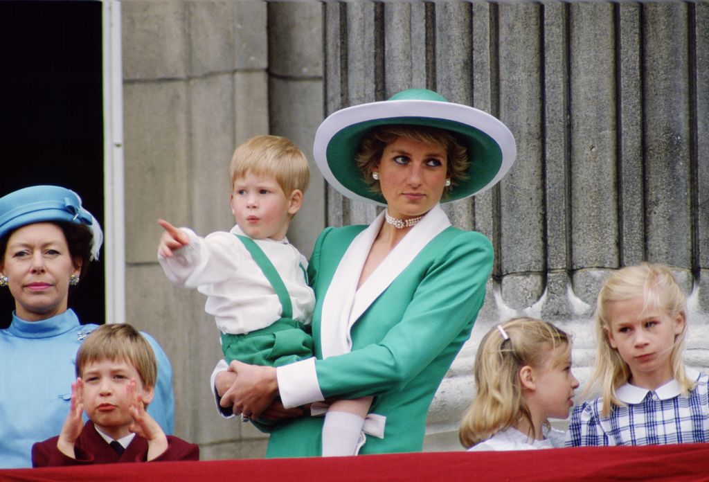 Diana, Princess of Wales, holding a young Prince Harry in her arms as she watches Trooping the Colour with Prince William, Lady Rose Windsor, Lady Davina Windsor and Princess Margaret from the balcony of Buckingham Palace  (Photo by Tim Graham Photo Library via Getty Images)