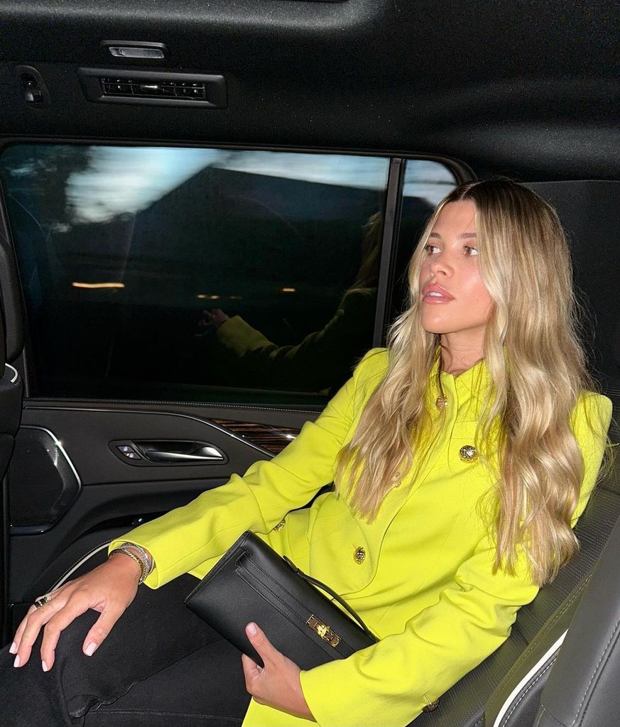 Sofia Richie wears a yellow blazer in the back of a car