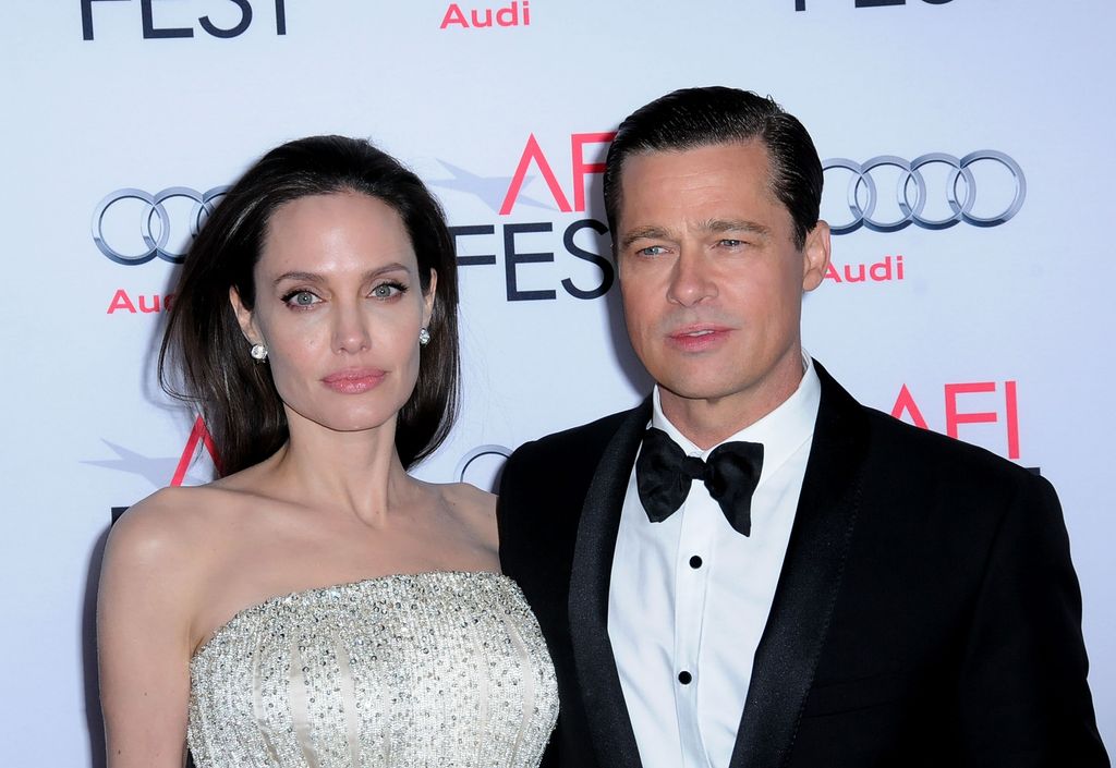 Angelina posing in a sparkly white dress with her arm around Brad Pitt in a bow and tie suit
