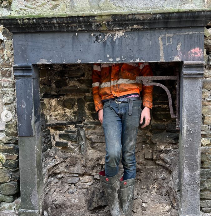 A child standing in a disused fireplace