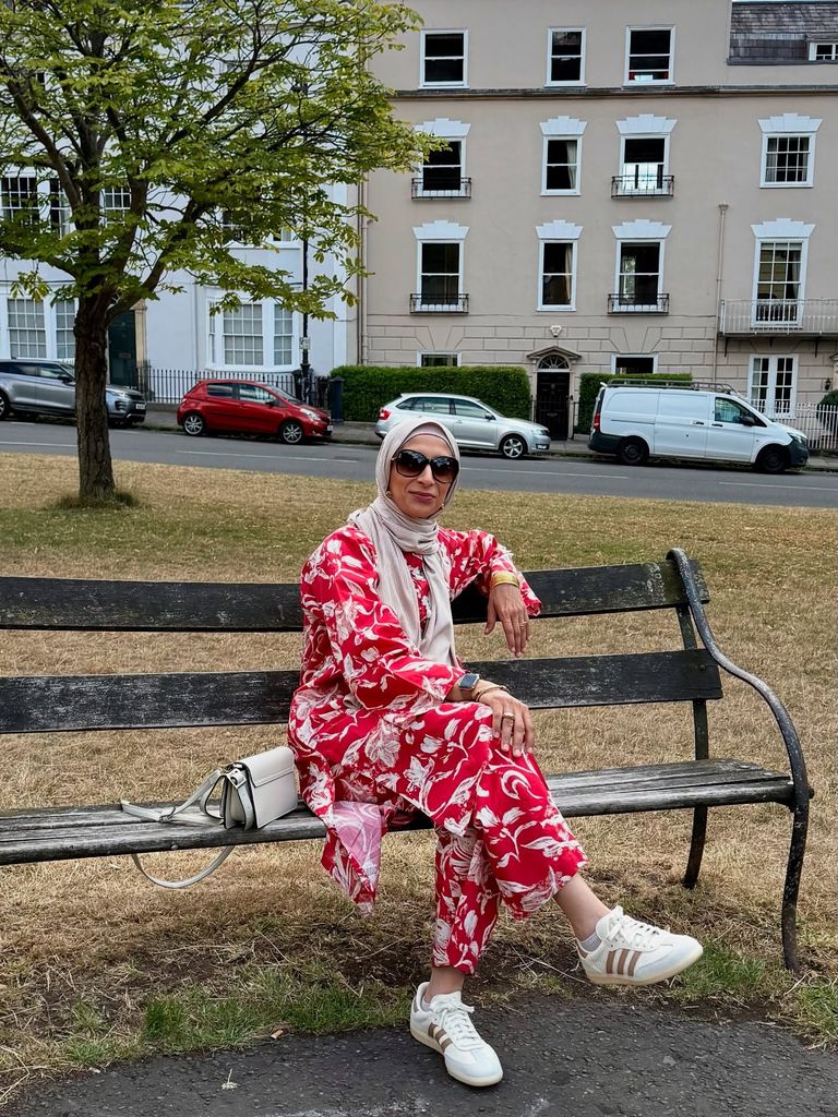 woman in headscarf and jazzy red outfit sitting on a bench 