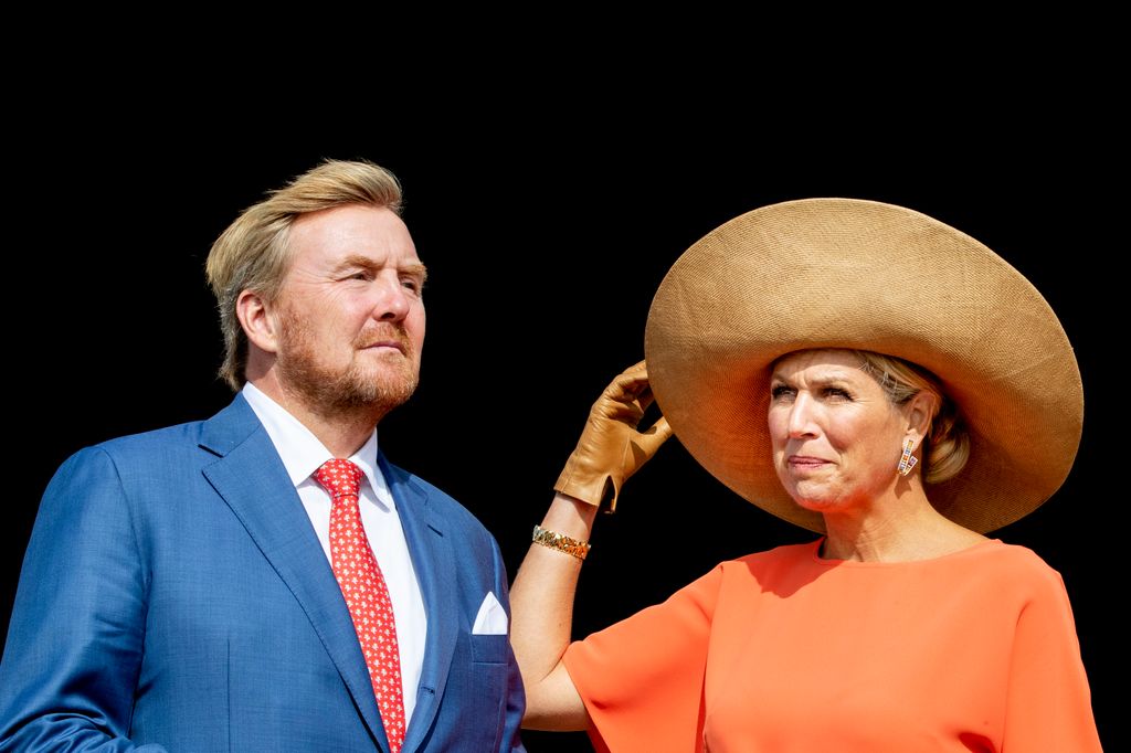 Queen Maxima wearing orange dress and wearing large hat