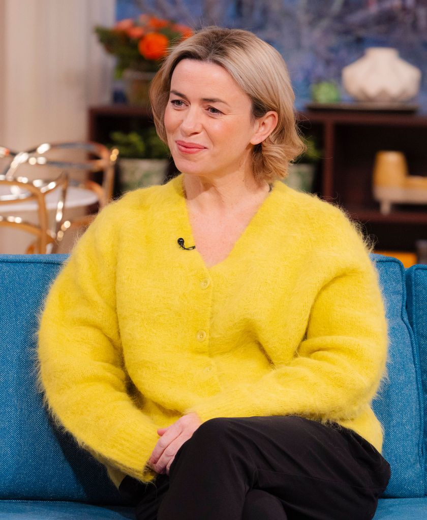 woman in yellow jumper sitting on blue sofa in tv studio