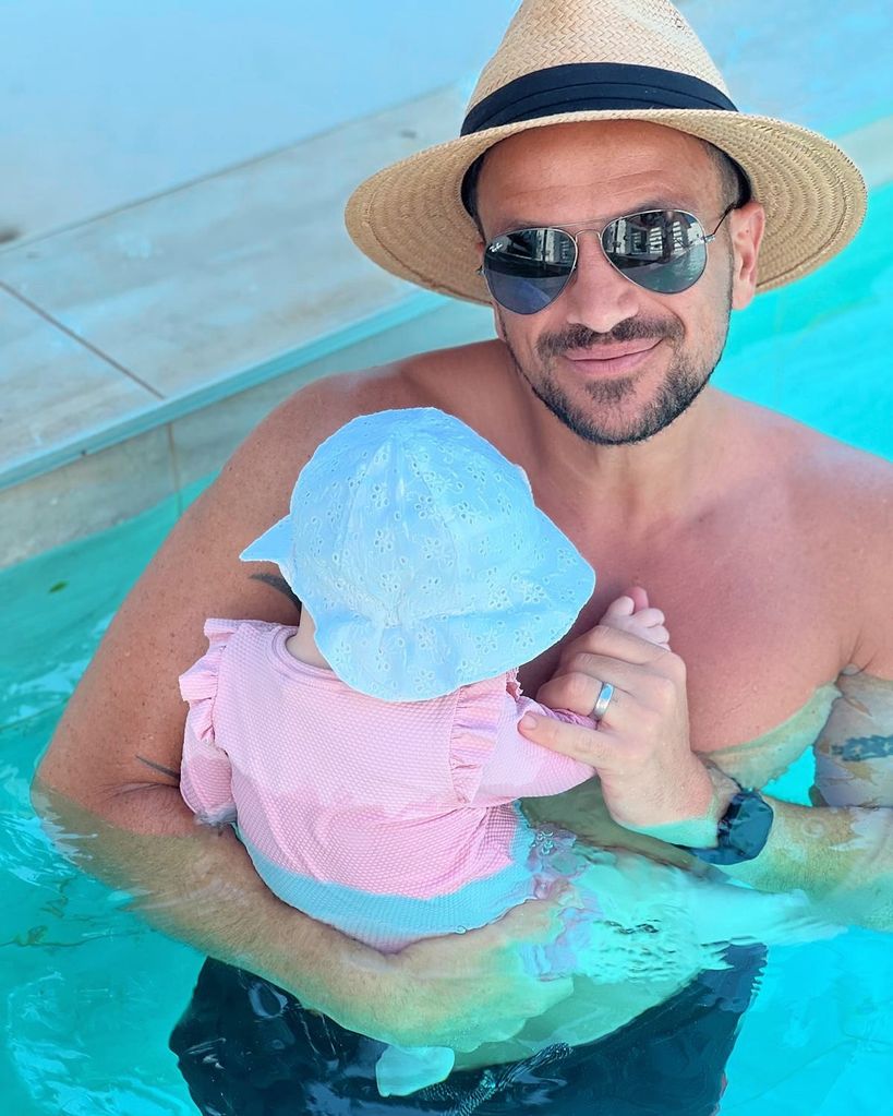 Peter andre holding his daughter in the pool