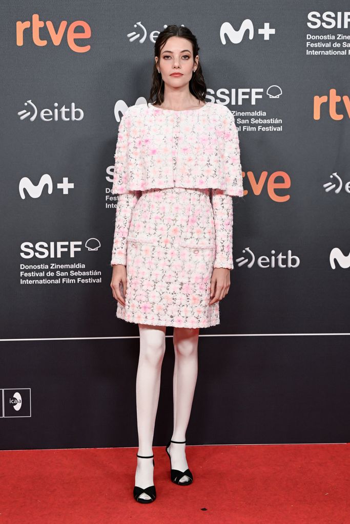 Mireia Oriol wears  textured pink floral mini dress brought a fresh, spring-like feel to the red carpet. The pastel color palette, paired with white tights and black accents on the shoes, made it whimsical yet refined. The structured cape-style top gave it a vintage nod, while keeping things ultra-modern.