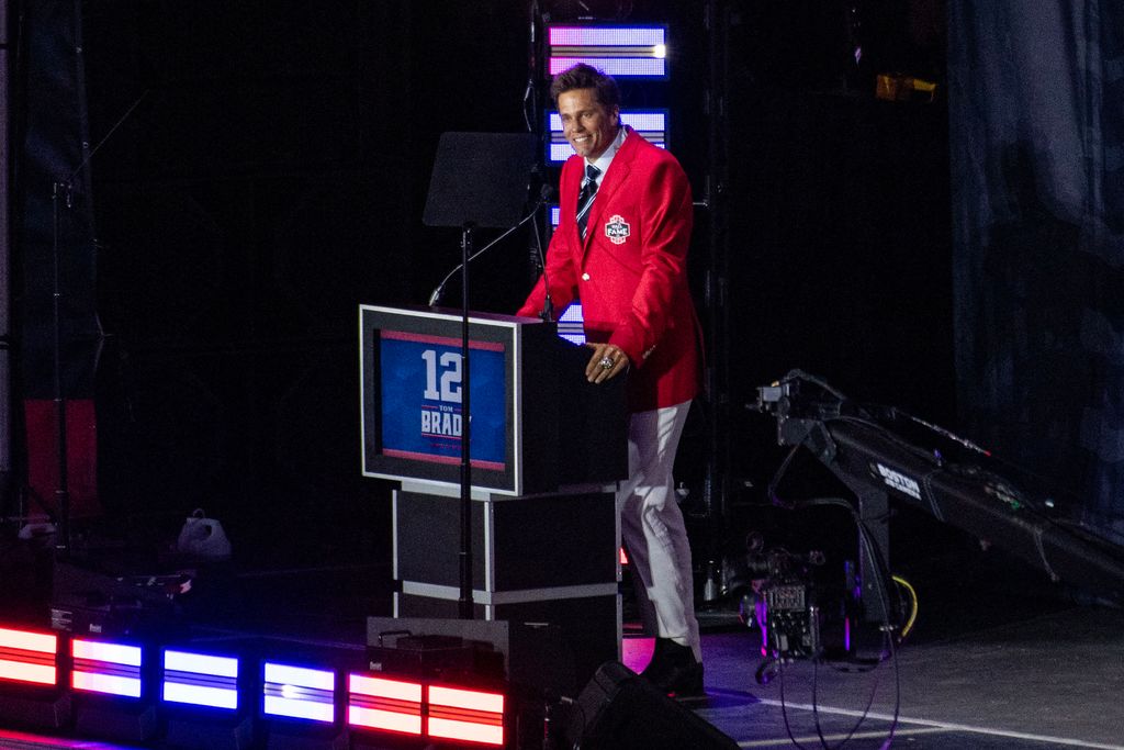 Former New England Patriots quarterback Tom Brady wears his red Patriots Hall of Fame induction jacket as he speaks during the 2024 induction ceremony at Gillette Stadium in Foxborough, Massachusetts, on June 12, 2024. Tom Brady is the 35th person to be inducted into the Patriots Hall of Fame.