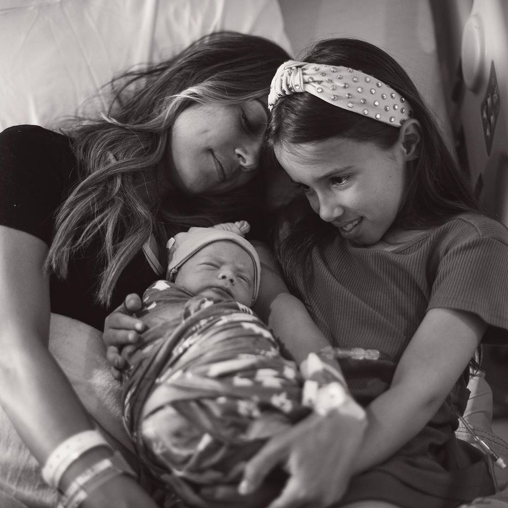 Jana cradles her newborn son with her daughter