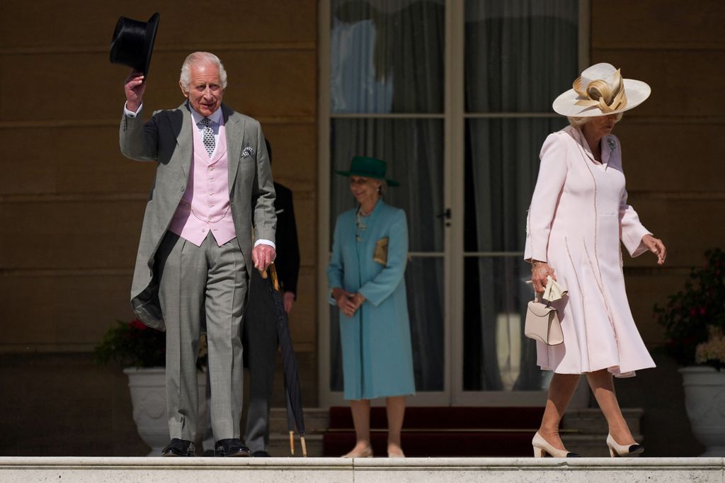 King Charles III raising his hat to his guests