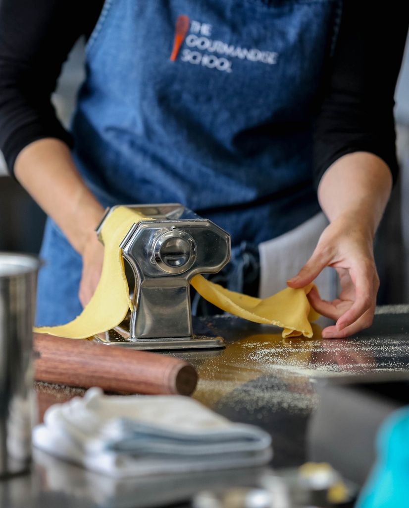 Person pulling pasta through pasta maker at the Gourmandise cooking school in Santa Monica