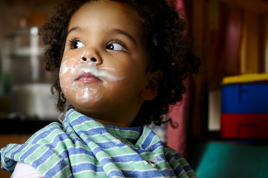 baby with curly hair and yoghurt around the mouth