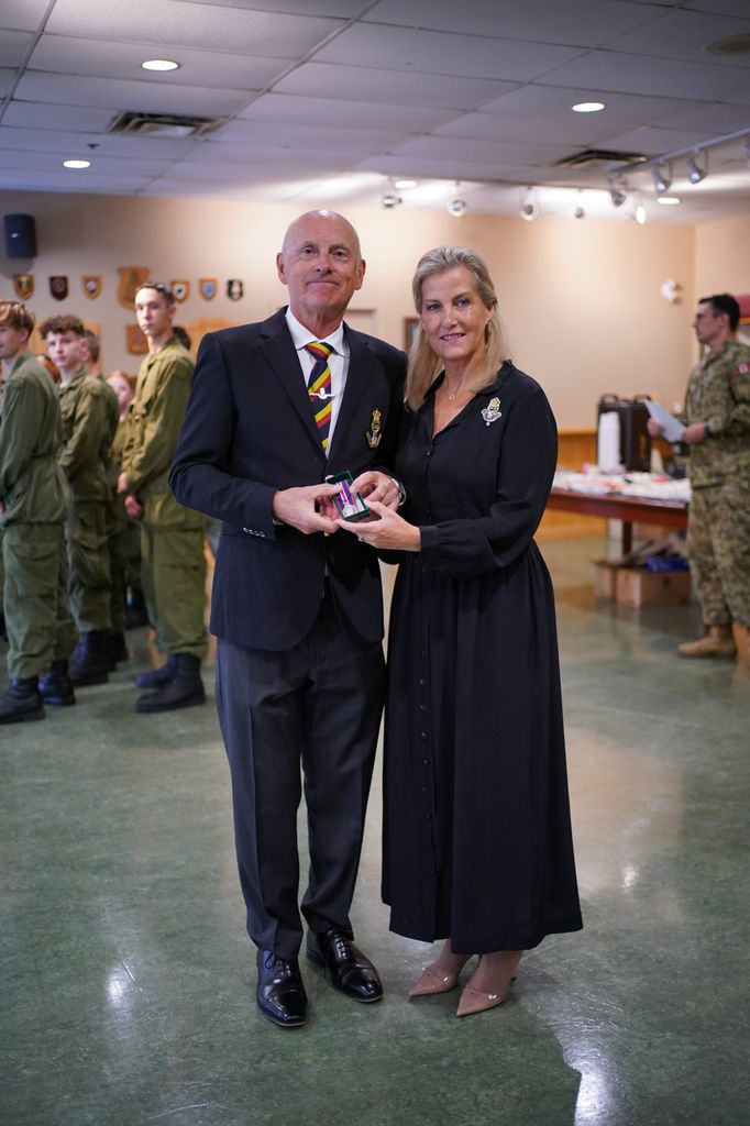 The Duchess of Edinburgh in black dress beside Lieutenant (retired) Richard Mack in suit 