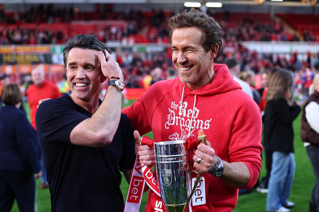 Rob McElhenney and Ryan Reynolds  co-owners of  Wrexham with the promotion trophy during  the Sky Bet League One match between Wrexham AFC and Charlton Athletic FC at Racecourse Ground on April 26, 2025 in Wrexham, Wales