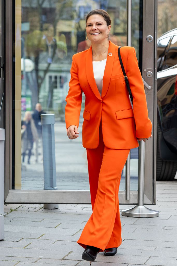 Crown Princess Victoria walking in bright orange suit