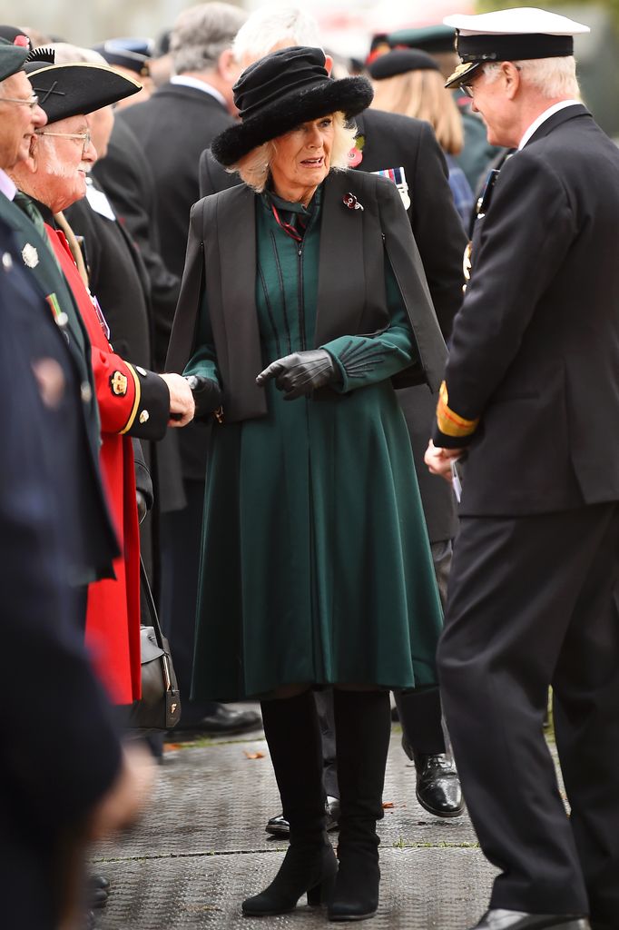 Queen Camilla in a green dress and cape with a fur hat