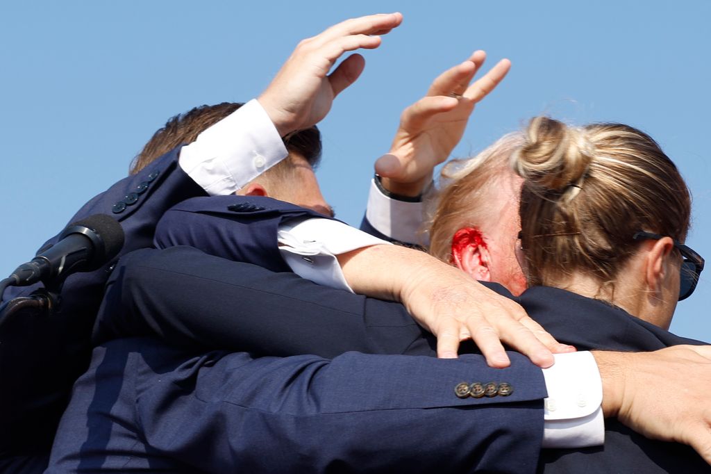 Blood rushes from Republican presidential candidate former President Donald Trump's ear as he is rushed offstage during a rally on July 13, 2024 in Butler, Pennsylvania