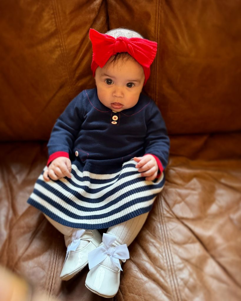 baby girl wearing striped dress and red bow 