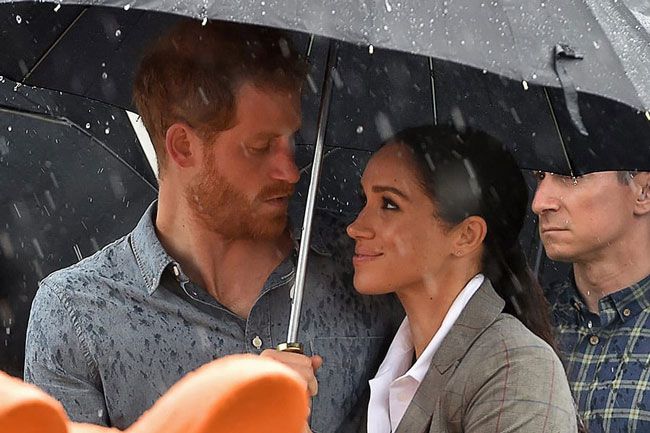 Harry and Meghan snuggle under an umbrella in 2018