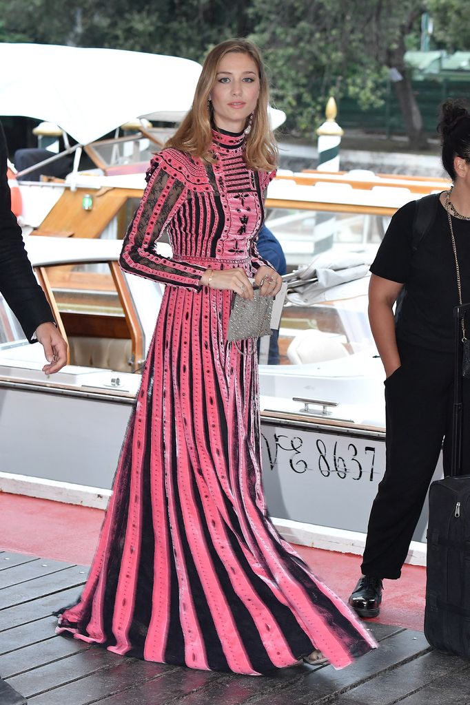 Beatrice Borromeo steps off a boat in Venice wearing a pink-and-black velvet gown with structured stripes and high-neck detailing during the film festival.