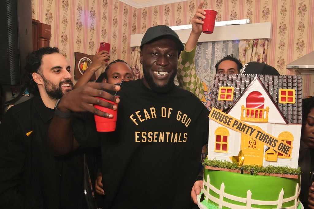 A photo of Stormzy with a house cake 
