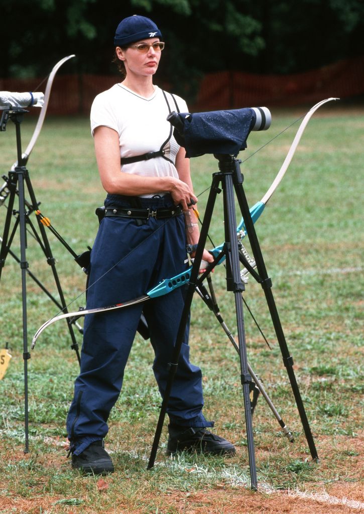 Gemma David in a white shirt and blue trousers with an archery bow