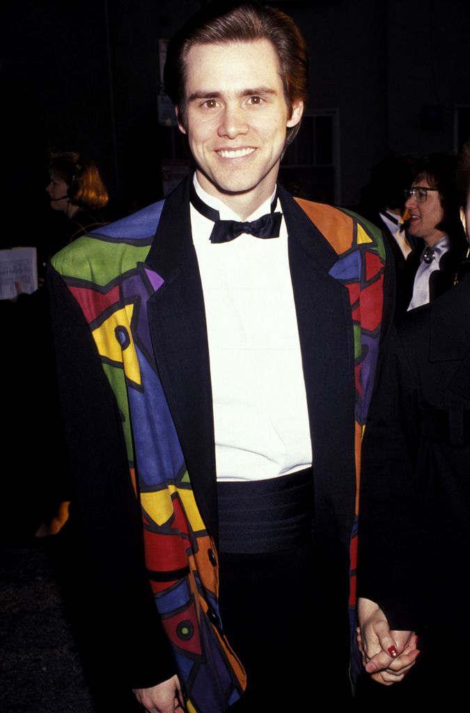 Jim Carey en costume et nœud papillon avec une veste graphique colorée.