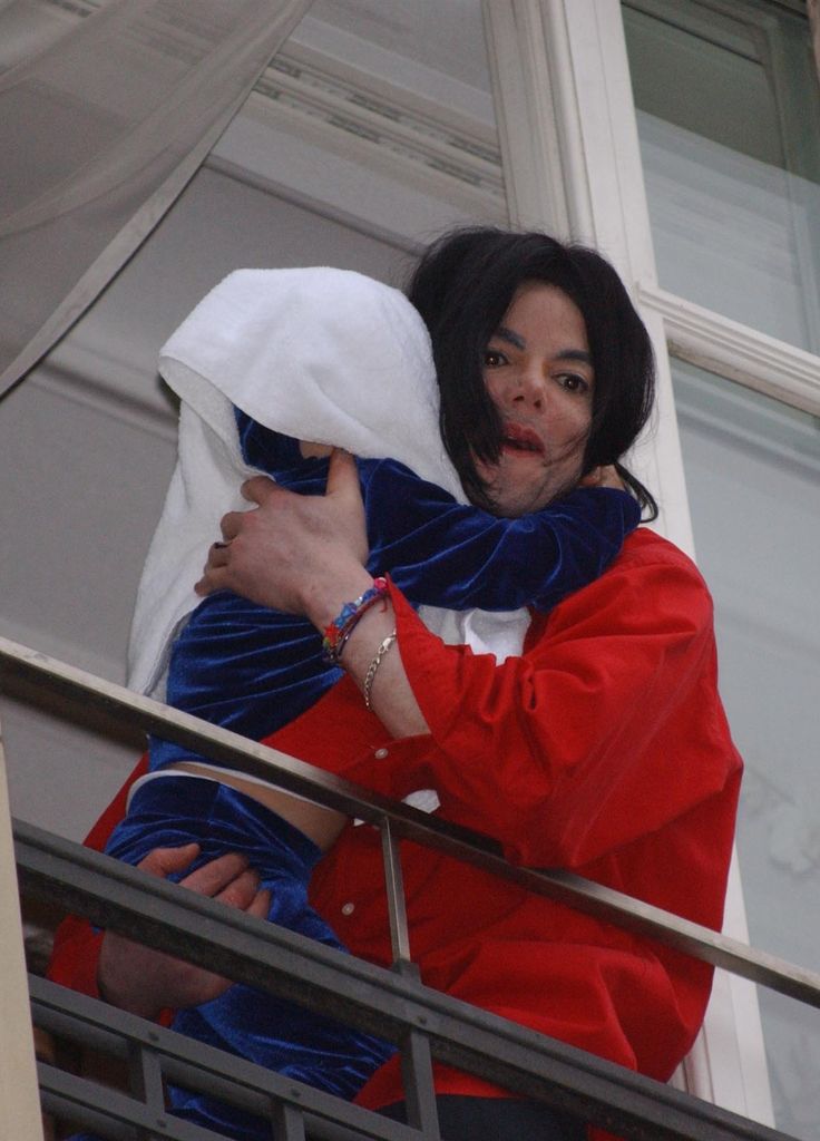 Michael Jackson dangles his son Bigi Jackson, covered with a blanket, from a hotel balcony in Berlin in 2002