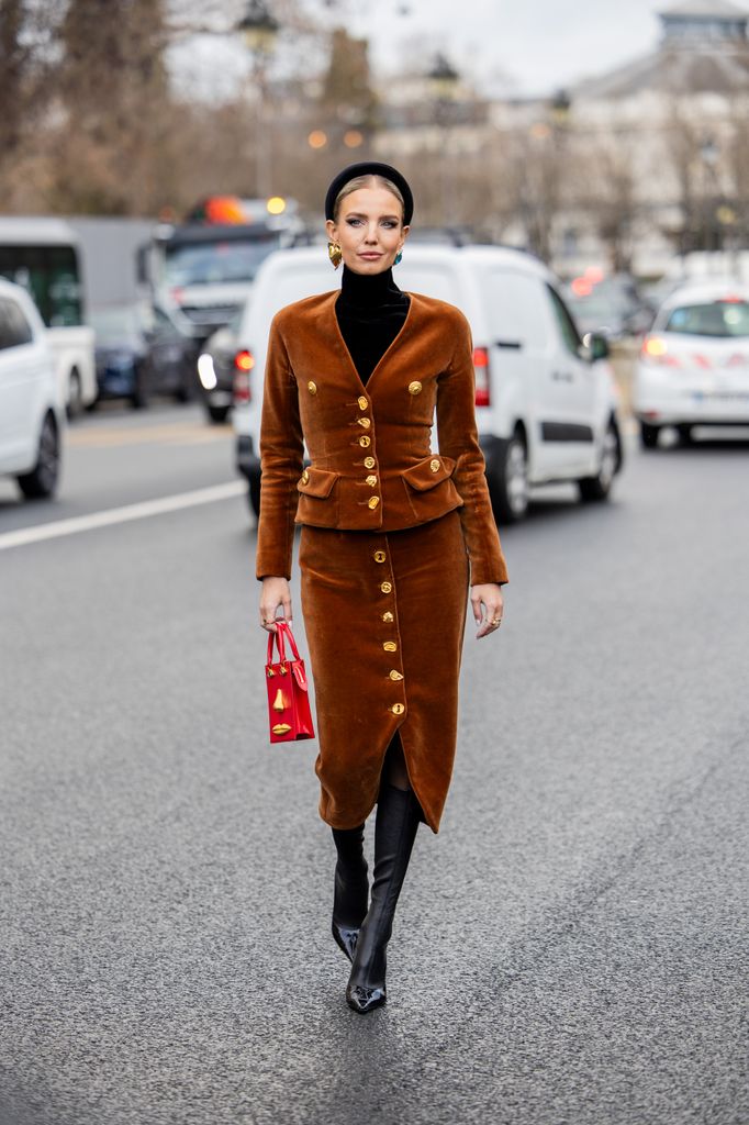 Leonie Hanne wears brown wild leather jacket, skirt, red bag, hair band, black boots outside Schiaparelli during the Haute Couture Spring/Summer 2024