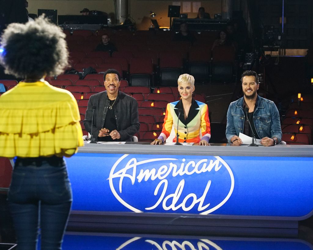 Katy sat a a judging table with Lionel and Luke on either side, a contestant is stood on the stage in front of them