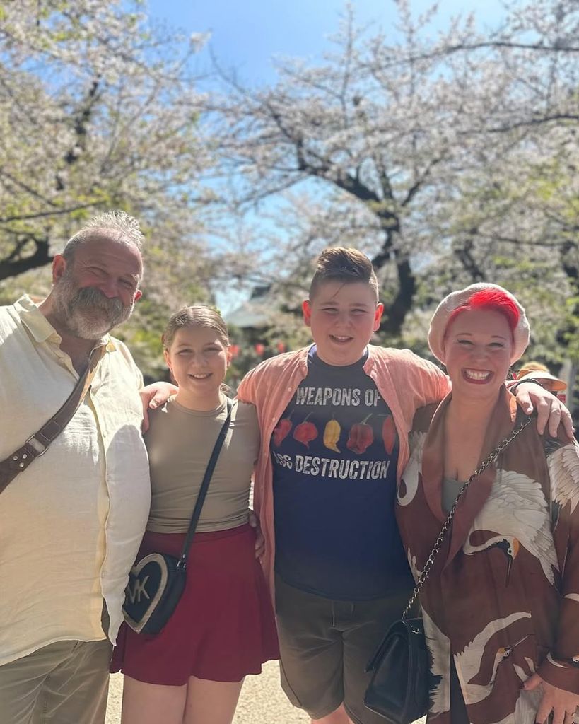 Dick and Angel Strawbridge standing with their two kids in the middle in front of a blossom tree during trip to Tokyo