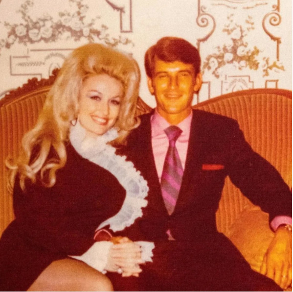 Dolly Parton smiling and sitting next to Carl Dean