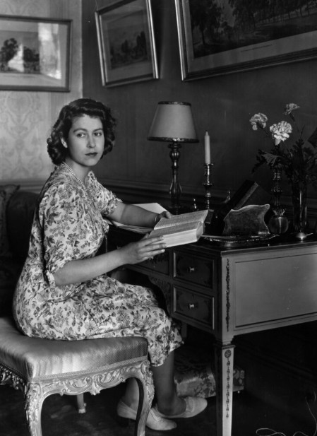 Queen Elizabeth writing and posing at her desk