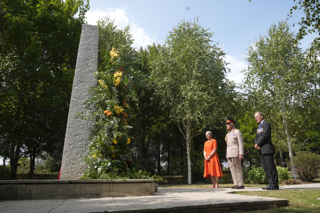 Britain's King Charles III (C) views a memorial alongside National Memorial Arboretum managing director, Philippa Rawlinson (L) and Royal British Legion National President, Vice Admiral Paul Bennett