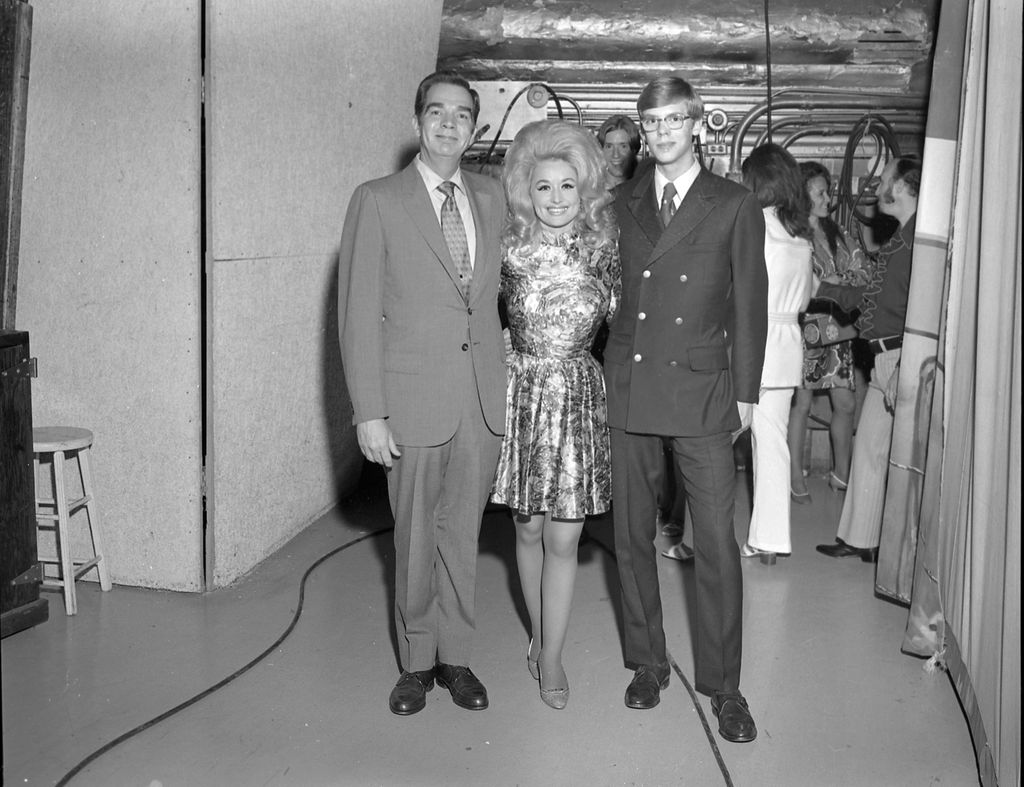 Dolly Parton poses for the camera with DJs backstage at the Grand Ole Opry circa 1970