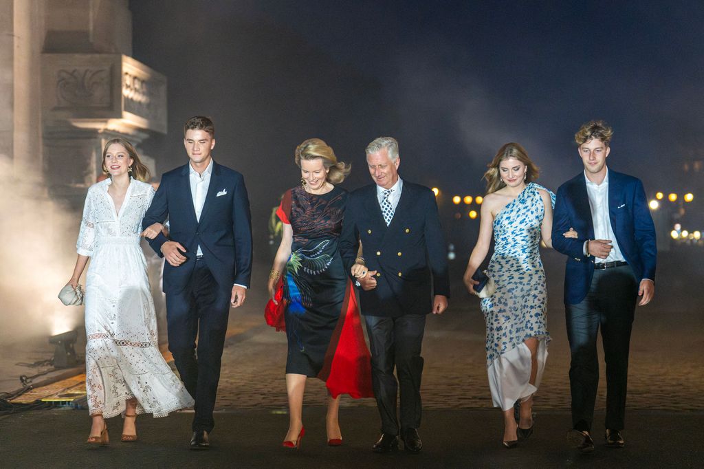 Princess Eleonore, Prince Gabriel, Queen Mathilde of Belgium, King Philippe, Crown Princess Elisabeth, Prince Emmanuel walk in a line arm in arm at night