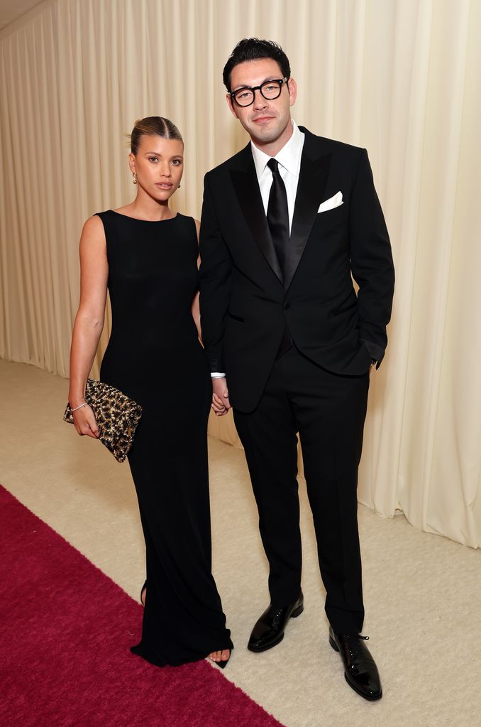 Sofia Richie in a black dress and Elliot Grainge in a suit and glasses