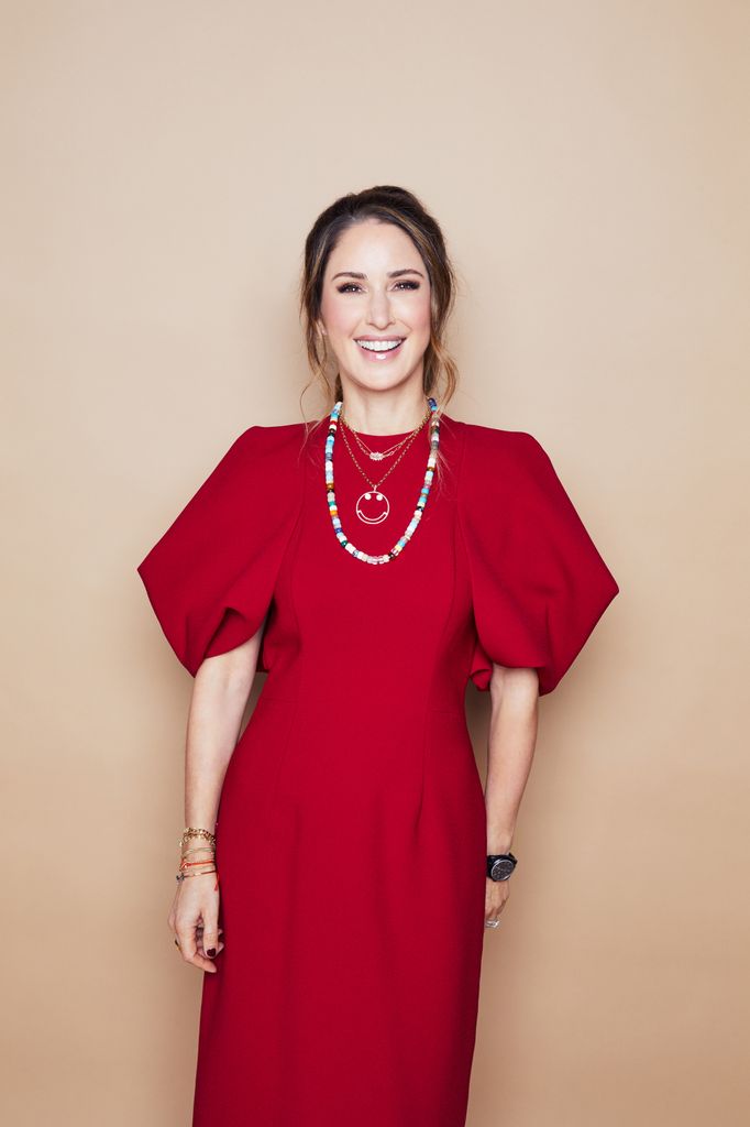 Smiling woman in a red dress against a neutral background