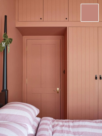 a pink painted room with stripey bed