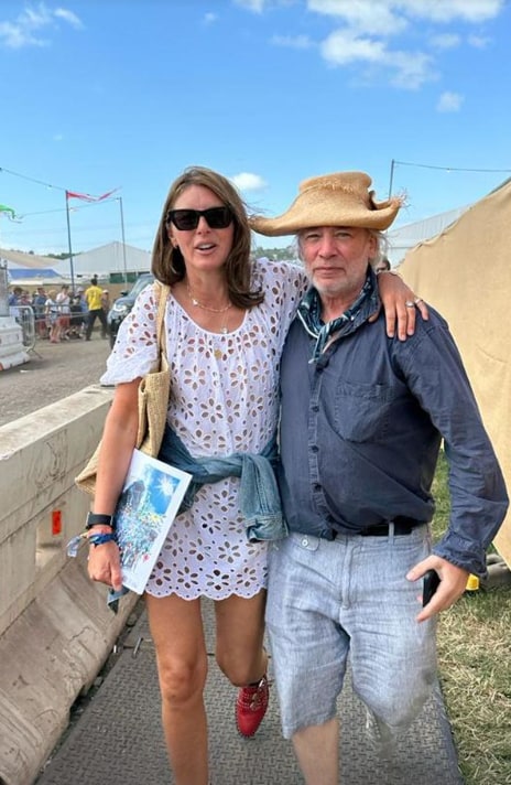 Jools Oliver wears white dress, denim jacket and red boots at Glastonbury